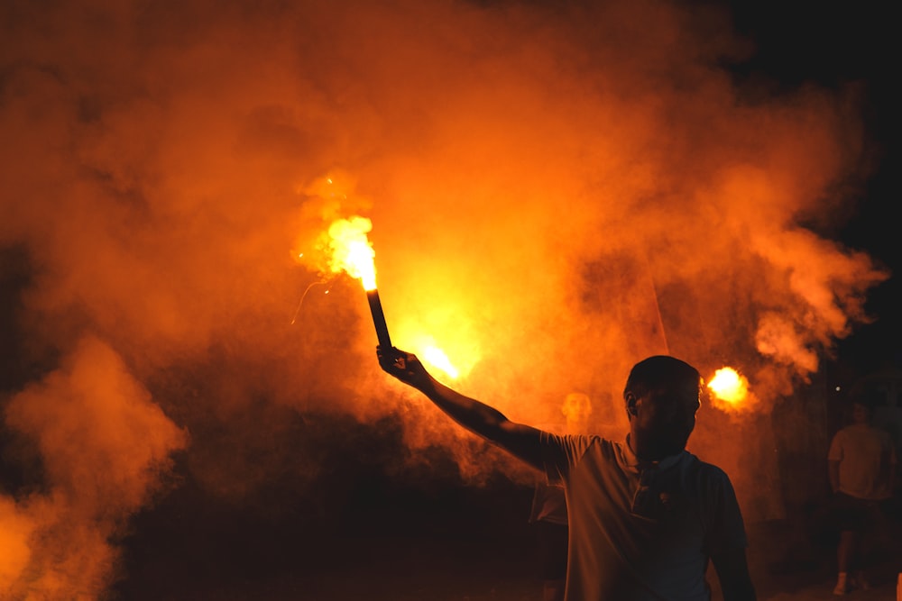 a man holding up a lit stick in front of a crowd of people