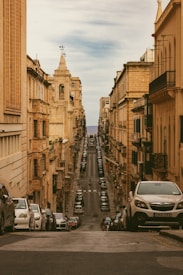 a city street lined with parked cars next to tall buildings