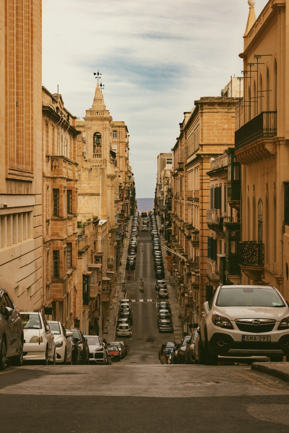 a city street lined with parked cars next to tall buildings