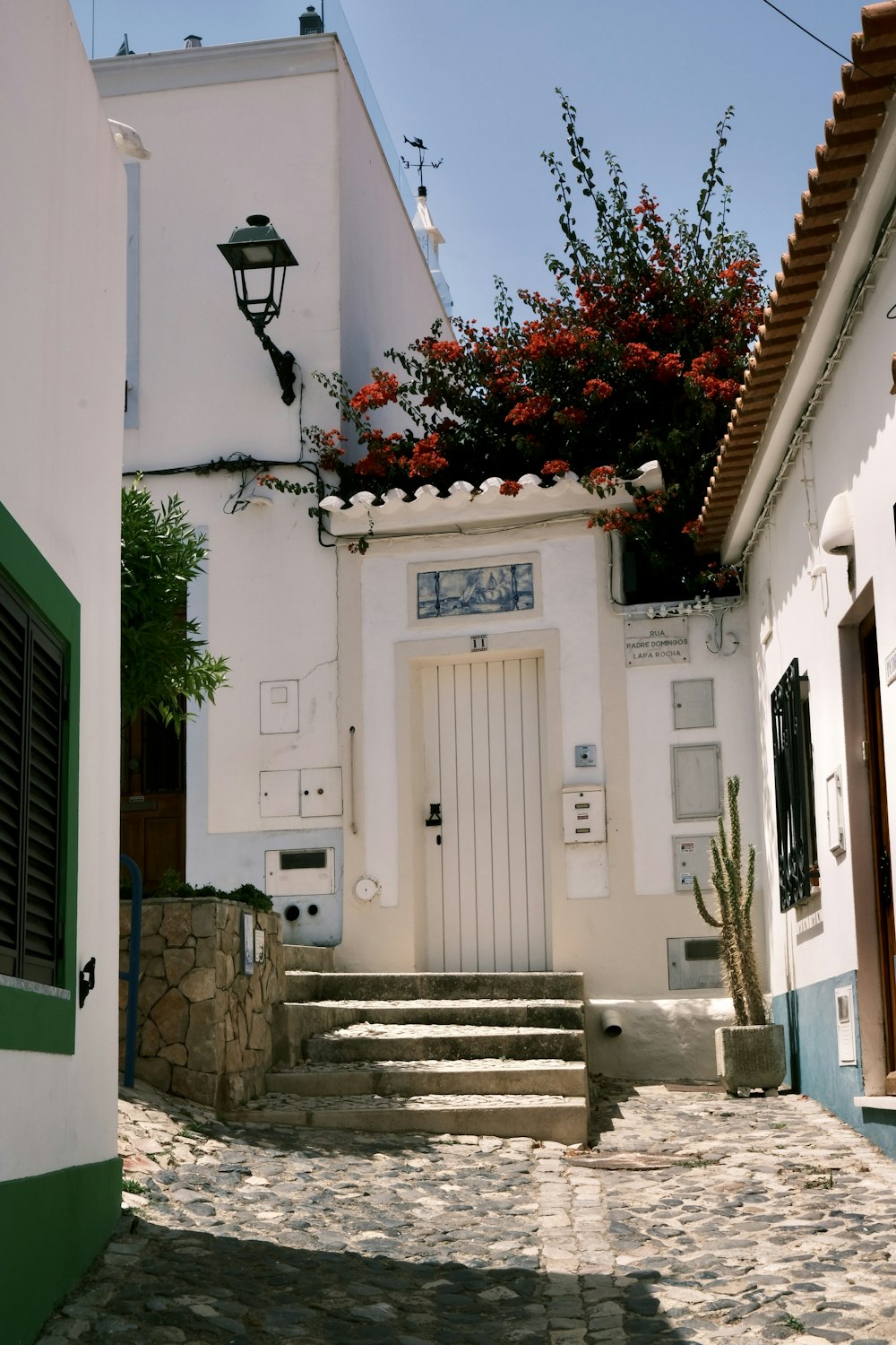 a cobblestone street with a white door and green shutters