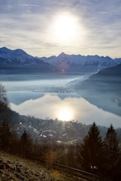 the sun is shining over the mountains and a lake