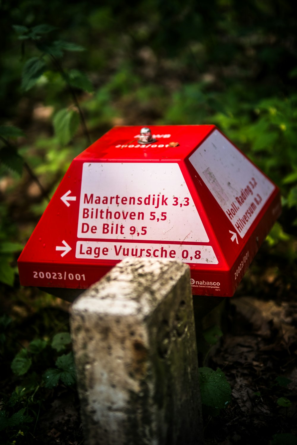 a red and white sign sitting on the side of a forest