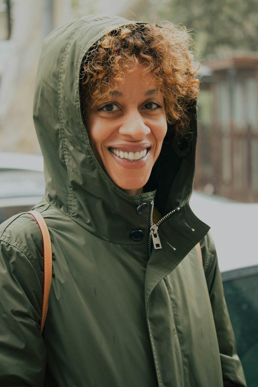 a woman with curly hair wearing a green jacket