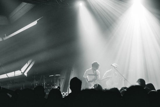 Dark urban photo of bxs & maig12 performing live on stage with intense lighting and crowd energy.