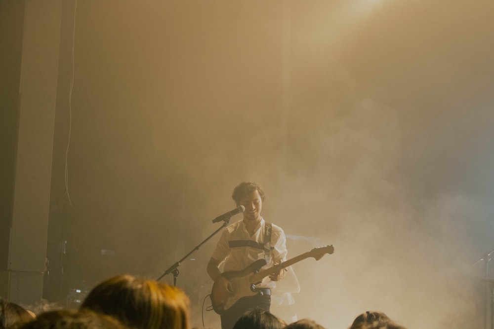 a man playing a guitar on stage in front of a crowd