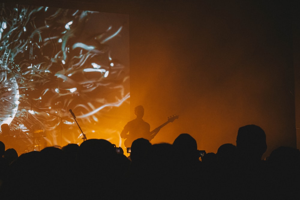 a man playing a guitar in front of a crowd