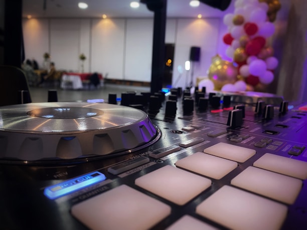Close-up of a DJ mixing music with colorful lights in the background during a wedding party.