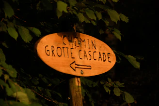 A rustic wooden sign marking the walking trail between Bienne and La Neuveville surrounded by lush greenery.