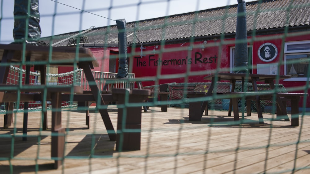 a wooden deck with tables and chairs behind a fence