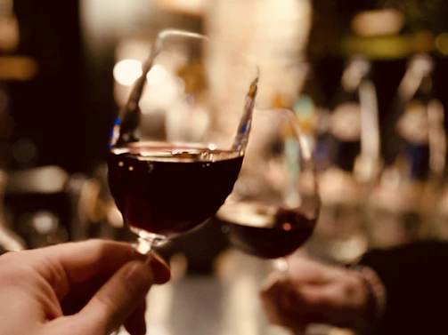 Close-up of hands clinking glasses of red wine in a cozy, friendly atmosphere.