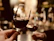 A softly lit close-up of a couple raising wine glasses in a toast at an elegant table with candlelight.