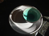A bright turquoise bowl resting on a wooden table with soft morning light.