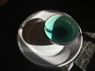 Close-up of a bright turquoise ceramic bowl with subtle texture and a matte finish sitting on a linen cloth.