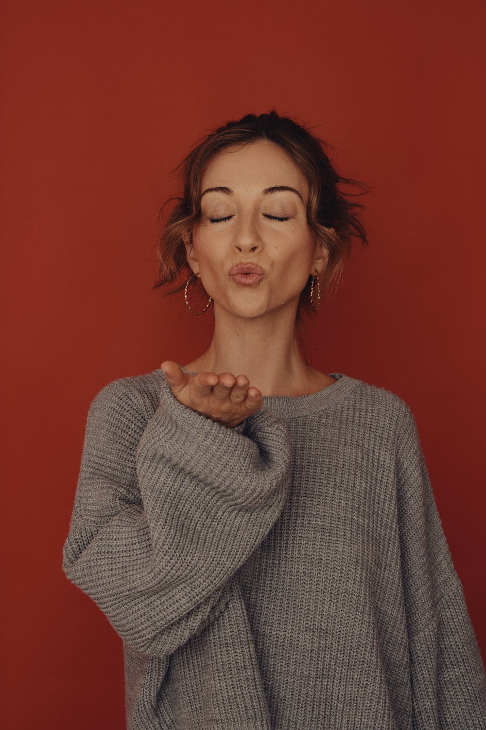 a woman with her eyes closed standing in front of a red wall