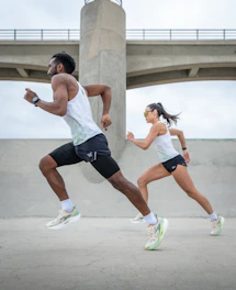 A man and a woman running side by side in white running kit