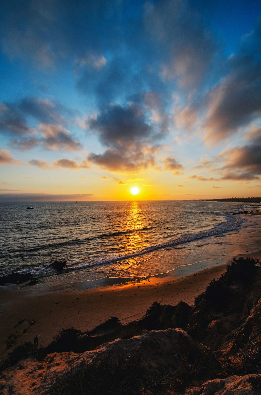 the sun is setting over the ocean on the beach