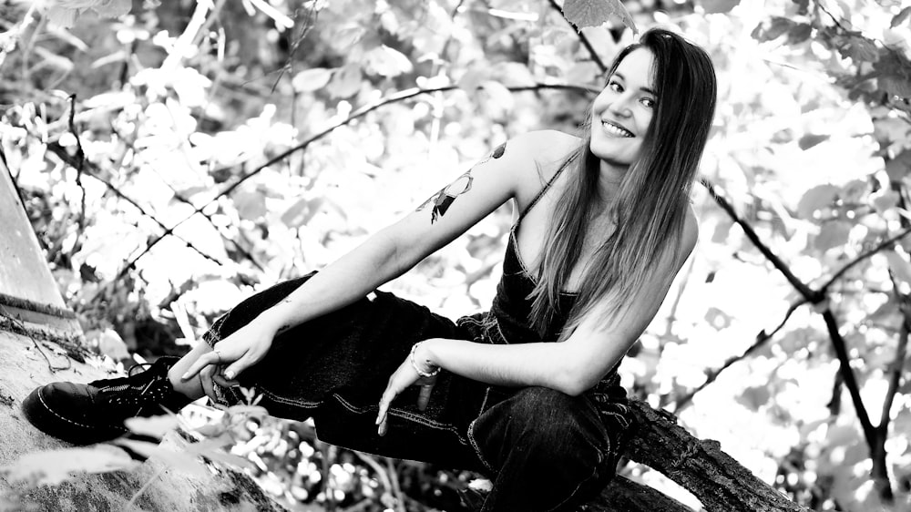Una foto in bianco e nero di una donna seduta su un ramo di un albero
