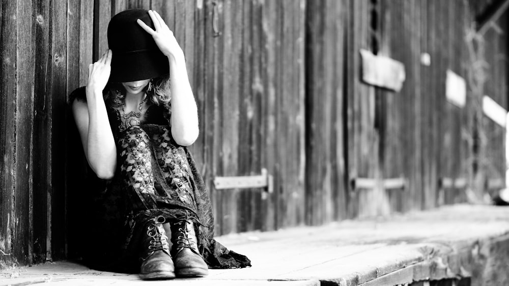 a woman sitting on a ledge with a hat on her head