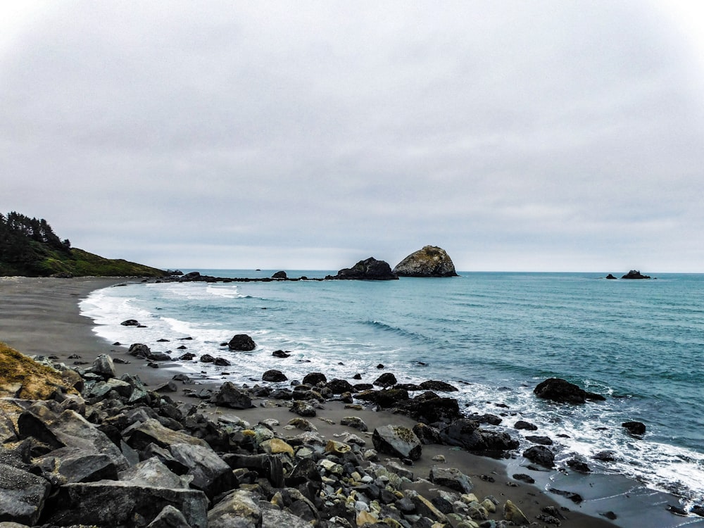 a rocky beach with a rock outcropping in the water