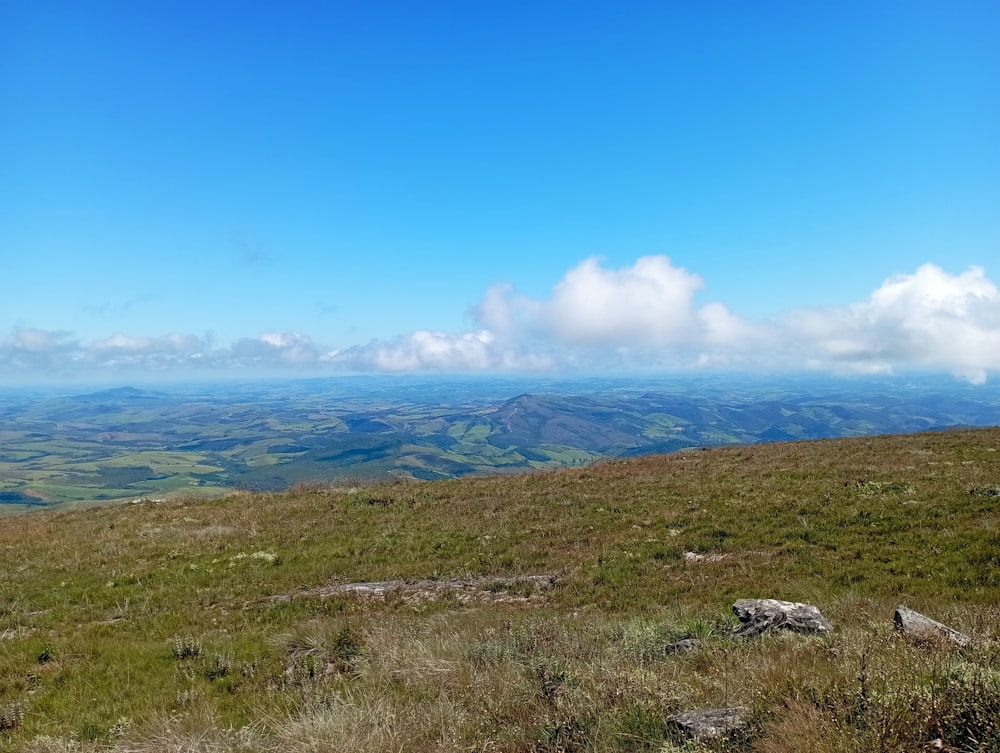 a grassy hill with a view of mountains in the distance