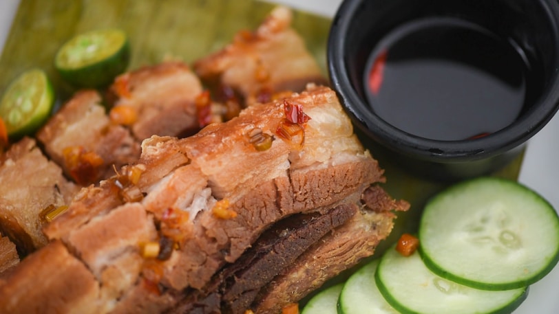 a close up of a plate of Lechon Pork Belly and cucumbers
