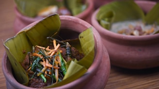 A rustic clay pot filled with steaming sambar, surrounded by fresh spices and banana leaves.