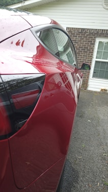 A clean, shiny car parked outside a modern home.