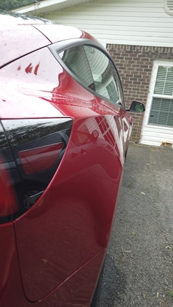 A shiny luxury car parked in a sunlit driveway with reflections on its polished surface