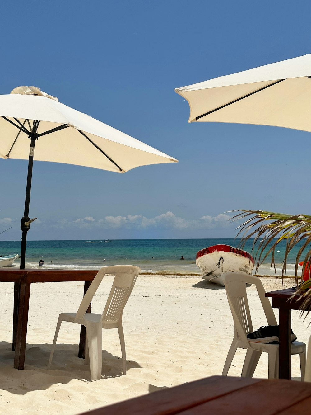 a couple of white chairs sitting on top of a sandy beach