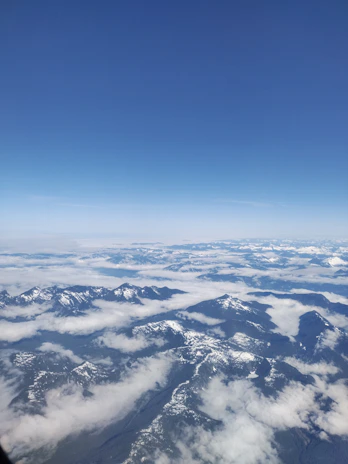 A panoramic view of the snow-capped peaks in the Swiss Alps under a bright blue sky.