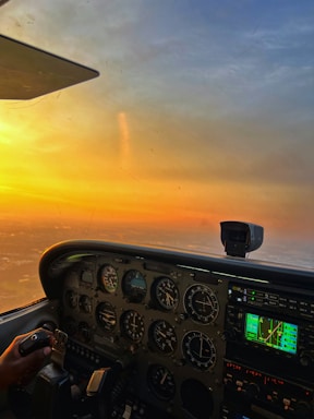 A sleek airplane cockpit with glowing instruments under a sunset sky.