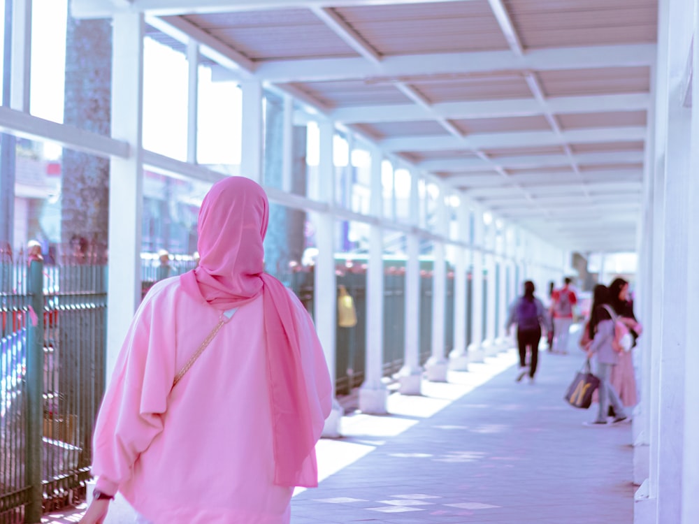 a woman in a pink hijab walking down a walkway