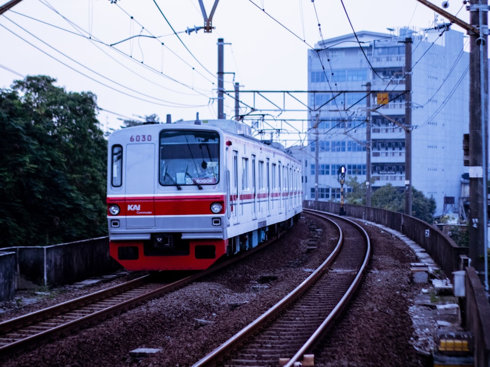 a red and white train traveling down train tracks