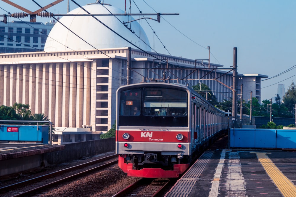 Un tren rojo y blanco que viaja por las vías del tren