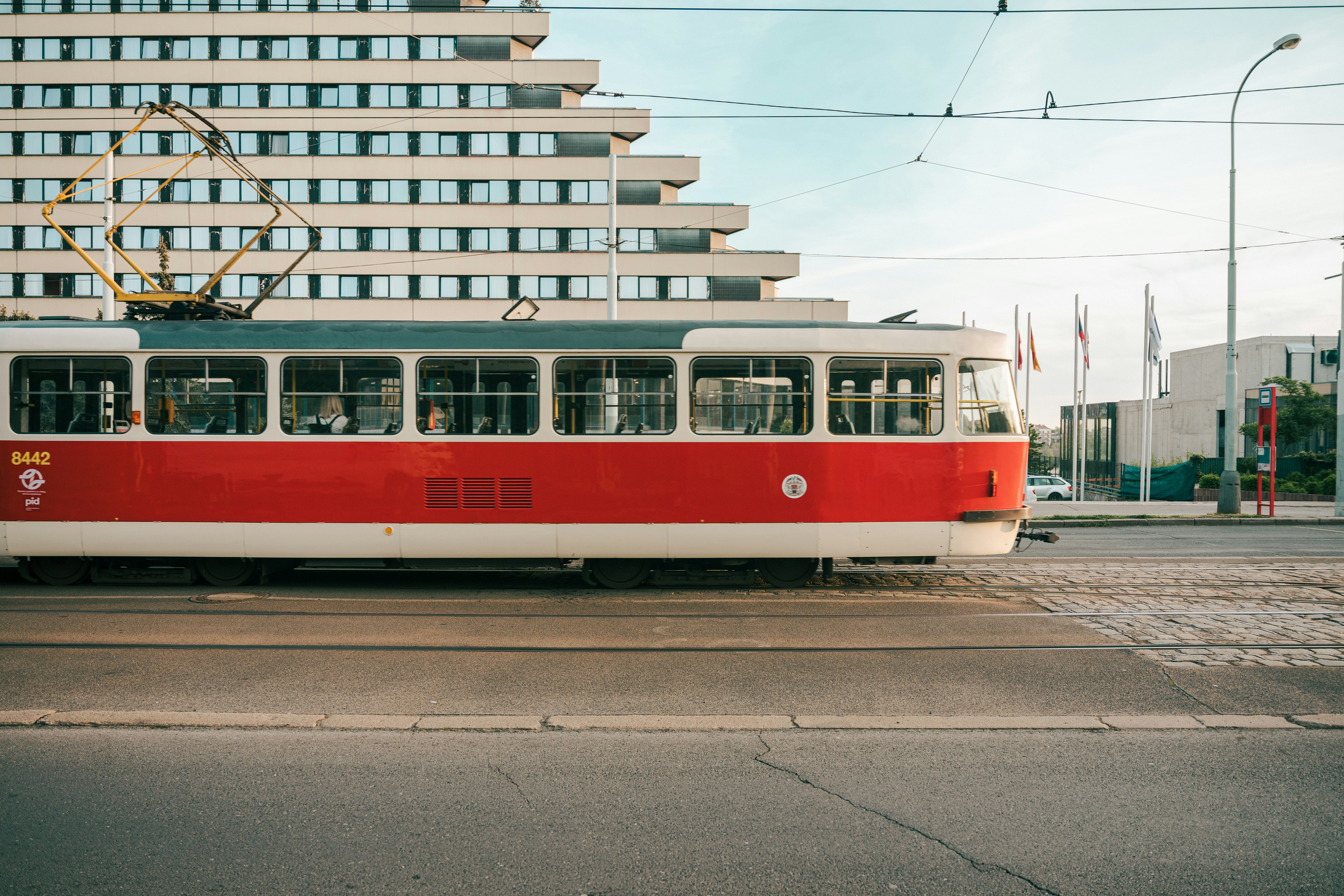 a red and white trolley on a city street, Touching down in Prague at 1 am, eager to embark on a weekend adventure. Waking up at 5:50 am to chase the morning light on a captivating walk. What a moment.