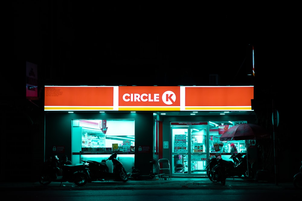 a store front at night with a motorcycle parked in front of it