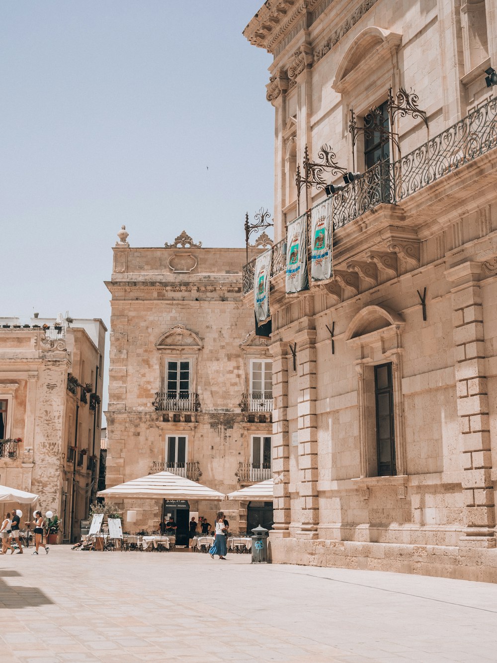 an old building with a lot of tables and umbrellas