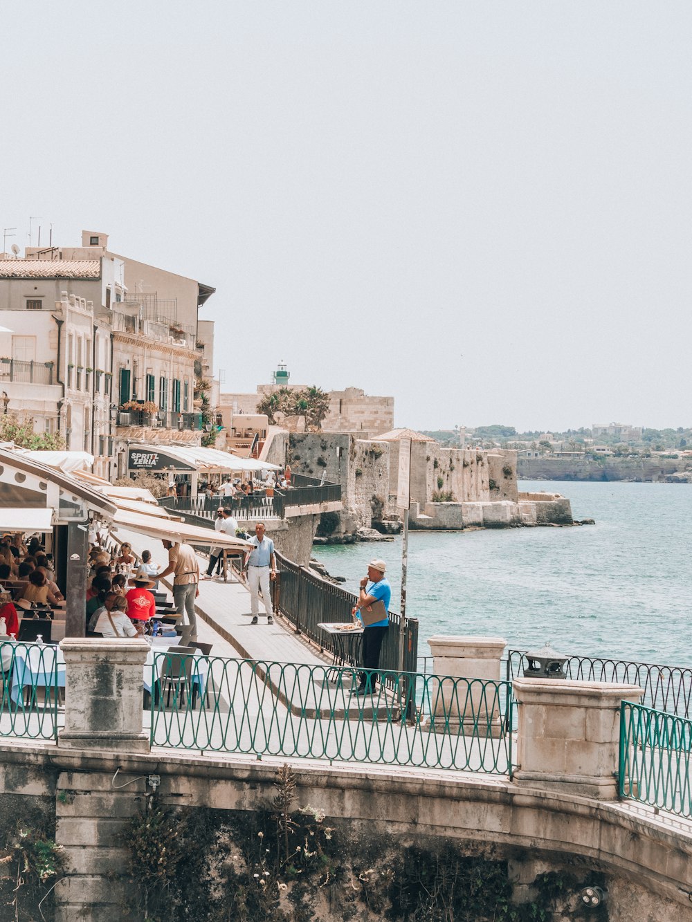 a group of people standing on a bridge next to a body of water