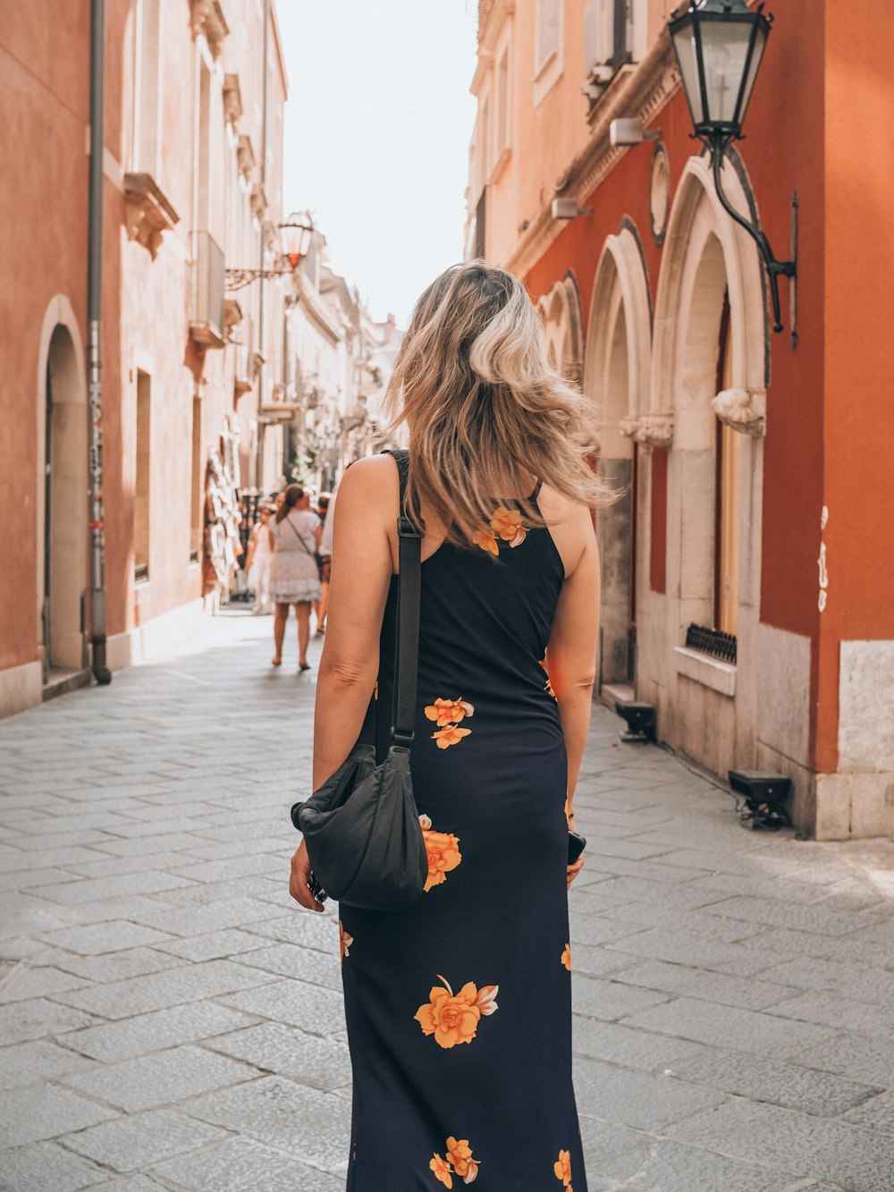 a woman in a black dress walking down a street