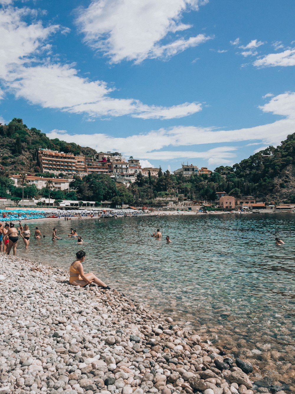 a group of people sitting on a beach next to a body of water