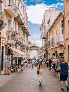a group of people walking down a street next to tall buildings