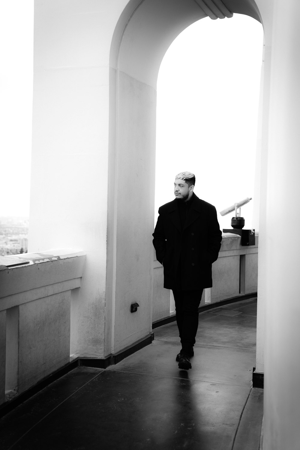 a man in a coat walking down a hallway