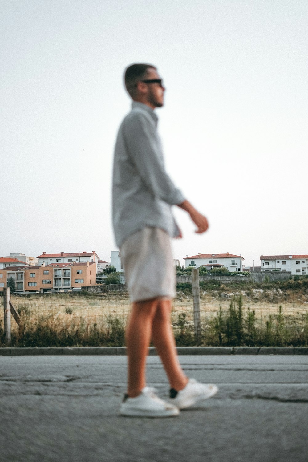 a man walking down the street in a white shirt and shorts