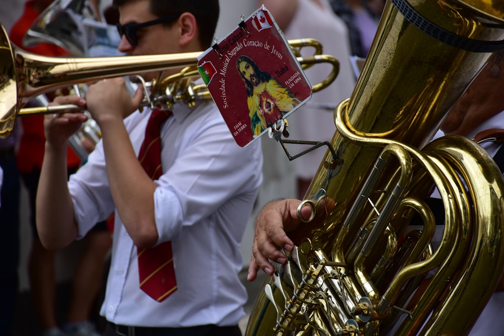 Un hombre con camisa blanca y corbata tocando una trompeta