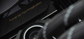 A close-up view of a mechanical or technological component with a sleek design and metallic textures is displayed. The phrase 'Power Up Your Imagination' is etched on the surface, suggesting encouragement or inspiration, possibly for creative or innovative activities.
