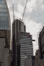 Aerial view of a modern commercial building under construction with cranes in the background.