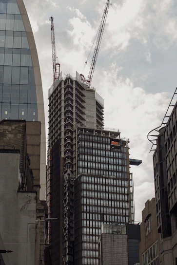 A panoramic view of a modern residential building under construction in Bahria Town, showcasing structural steel frameworks and cranes against a clear sky.