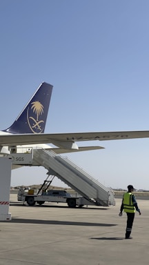 A friendly airport ground staff member assisting a trainee near an airplane.