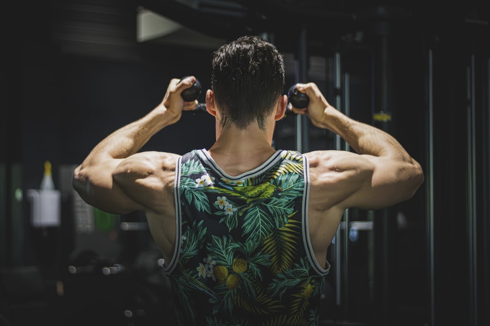 a man in a tank top is doing exercises in a gym