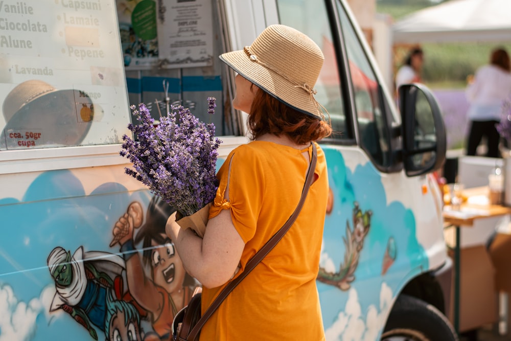 a woman in a straw hat holding a bunch of lavenders